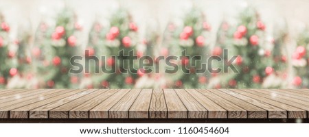 Empty rustic wood plank table top with abstract blur christmas tree red decor ball and snow fall background with bokeh light,winter Holiday backdrop,Mock up banner for display of product or promotion