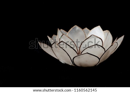 Decorative lotus flower made of gold coloured iron and glass petals against a black background