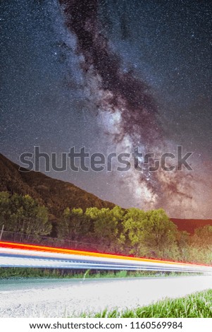 Night astrophotography: The Milky Way over Pyrenees in Vall de Boí with vehicles running through the road, Catalunya, Spain