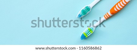 Two toothbrushes lie on a pastel blue background. Top view, flat lay. Minimal concept