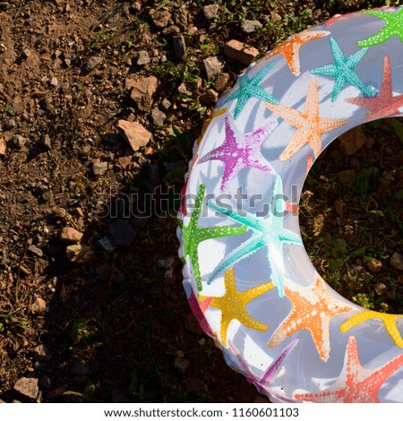 Bright children's inflatable circle lying on the ground on the beach. Lifeline is white with a picture of a starfish
