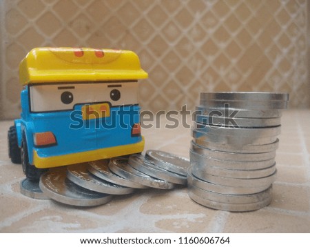 a miniature car with a brown background among a pile of silver coins