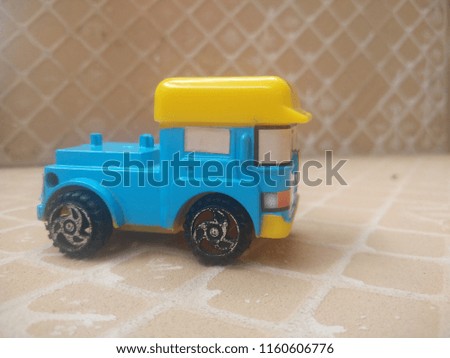 a miniature car with a brown background among a pile of silver coins
