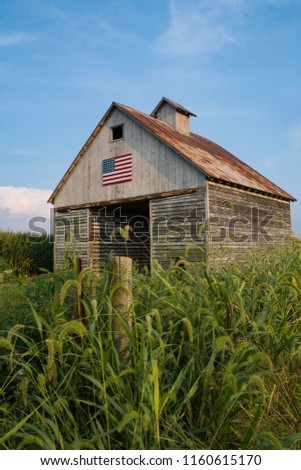 Old wooden barn with American flag painted on the side on a Summer afternoon.  LaSalle County, Illinois, USA