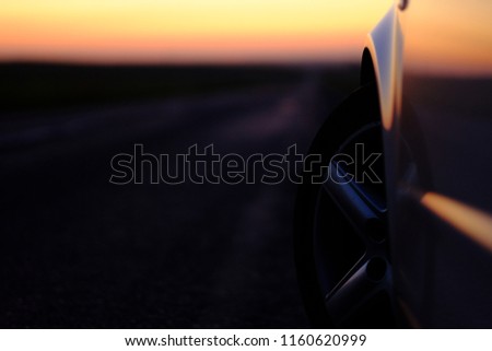The wheels of a sport car at dusk, with the asphalt at foreground, in a racetrack. Car in a racetrack.
