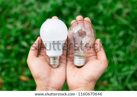 Alternative technology concept . Hands holding LED Bulb and Fluorescent bulb comparing in hands . copy space for text . Royalty-Free Stock Photo #1160670646