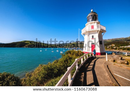 A beautiful lighthouse locate in Akaroa, New Zealand. This is a perfect holiday destination. It is popular among tourists, backpackers, and locals. One can enjoy clear blue sky, ocean, and shops. Royalty-Free Stock Photo #1160673088