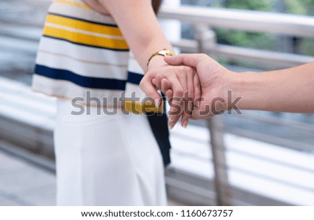 Close up the asian couple holding hand, follow me, selective focus at hand
