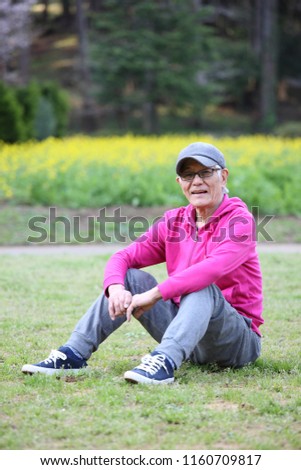 senior Japanese man in a hoodie sitting on a lawn