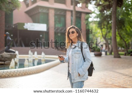 Young caucasian girl is walking on the street and listening to music.