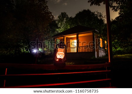 Horror Halloween concept. Burning old oil lamp in forest at night. Night scenery of a nightmare scene. Selective focus.
