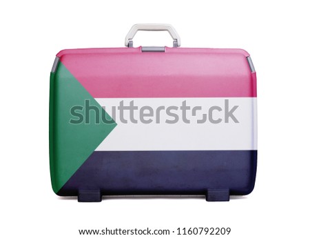 Used plastic suitcase with stains and scratches, printed with flag, Sudan