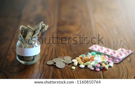 Drugs and coins in a glass jar on a wooden floor. Pocket savings from coins in a bank for medical services. Piggy bank in a jar with coins.
