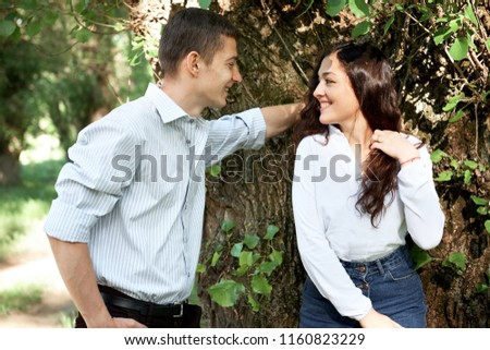 young couple walking in the forest, posing near tree, summer nature, bright sunlight, shadows and green leaves, romantic feelings