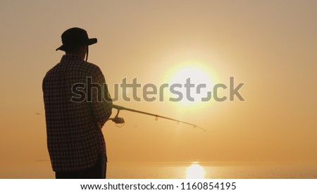Hobbies and activities - a young man is fishing on the beach at sunset