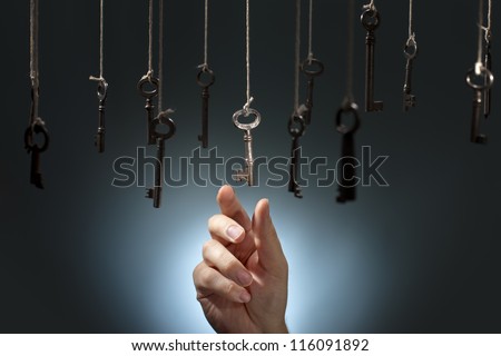 Hand choosing a hanging key amongst other ones. Royalty-Free Stock Photo #116091892