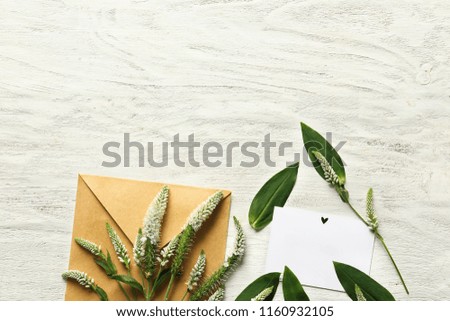 Beautiful flowers with envelope and card on white wooden background