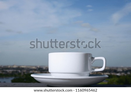 coffee cup on a background of blue sky .
Hot coffee cup on black floor and city village with blur house Orange roof background.  