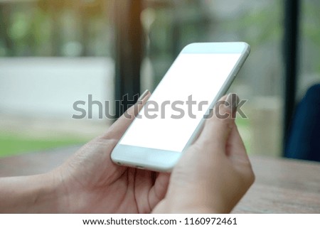 Mockup image of a woman holding white smart phone with blank desktop screen with green nature background