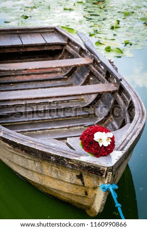 Wedding bouquet on wooden boat, romantic picture on wedding day, bridal bouquet with red peonies and white orchids, in summer