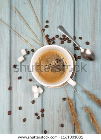 A cup of coffee with sugar, coffee spoon and spikelets on a soft blue painted wooden background. Flat lay photo