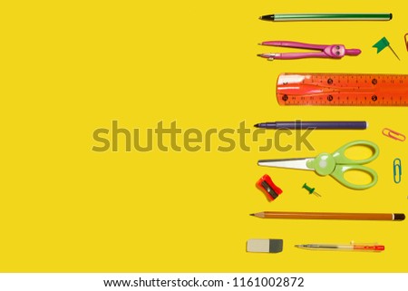 row of different school and office stationary and gadgets lying on a yellow background. free space for advertising text