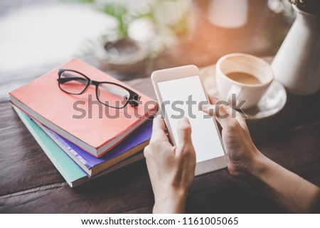 Close up hand holding young woman a smart phone with a blank white screen in a cafe, touching smartphone screen. Mockup portrait.