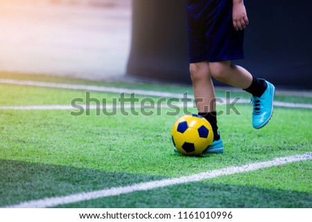 kid soccer trap and control ball on green artificial turf for shoot to goal. He put blue  sport shoes. Kid soccer learning football. It is activity on holiday.