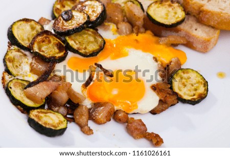 Image of plate with scrambled  eggs with lard and zucchini at table on table