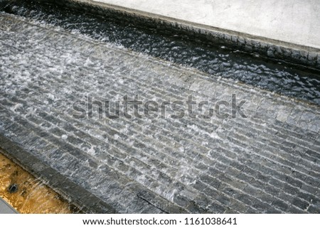 Waterfall wall, Waterfall on the black stone wall. Landscape design detail