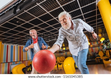 Great throw. Cheerful positive man smiling while throwing the bowling ball
