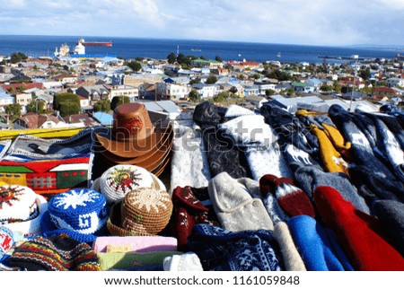 A lot of bright colorful sweaters  and hats on the background of a small South American town and the sea