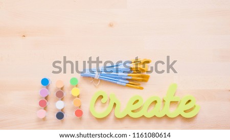 Green create sign with paint brushes on the table.