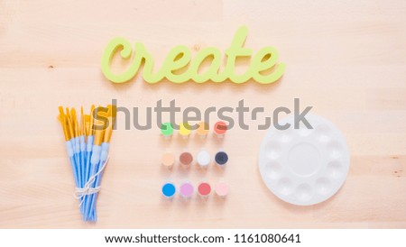 Green create sign with paint brushes on the table.