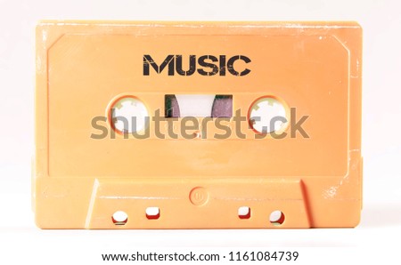A vintage cassette tape from the 1980s era (obsolete music technology) with the text Music printed over it (my addition, not in the original image). Color: cream, sand. White background.
