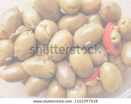 Green Olives (Olea europaea sylvestris) vegetables with hot chilli peppers vegetarian food in a plastic tub, delicate soft faded tone useful as background