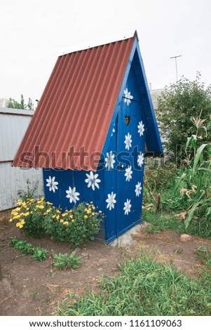 outdoor wooden toilet painted blue with a white flower