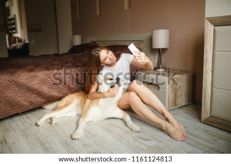Girl taking a selfie with her dog. Pretty girl and her dog taking a selfie on the floor in bedroom. Cute  dog posing for a selfie with his owner