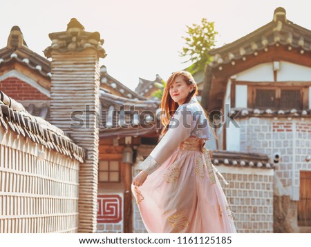 travel and tourist korea concept from beautiful woman in korea traditional cloth (hanbok) relax, take picture in vintage town with rim light and soft focus background