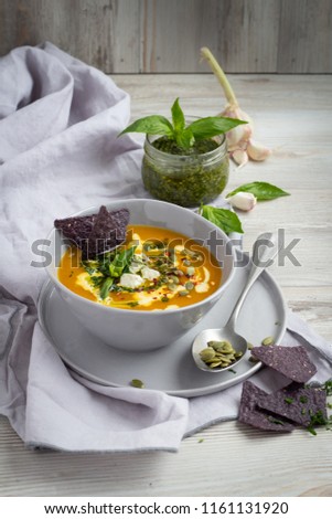Pumpkin cream soup with pesto and black corn chips