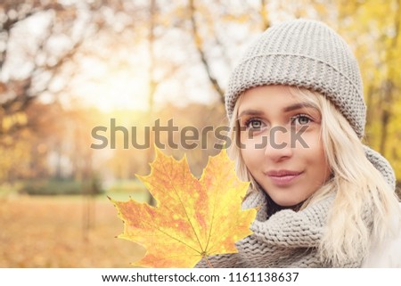 Beautiful autumn woman holding yellow maple leaf outdoors. Romantic girl on fall park background