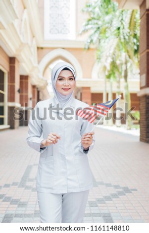 Malaysian independent day concept - Portrait of muslim asian female doctor and nurse holding Malaysian Flag