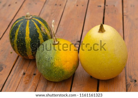 Three pumpkins of different varieties on a wooden surface. Vintage
