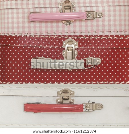 close up image of pink suitcases with polka dots over pink background texture