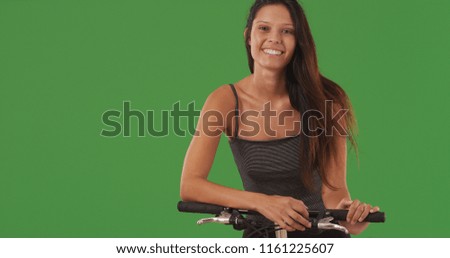 Closeup of lovely white girl smiling seated on bicycle in front of greenscreen