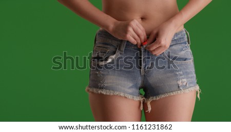 Close-up young attractive woman wearing cut off shorts isolated on green screen