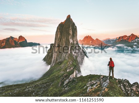 Traveler hiking on mountains ridge over clouds adventure journey traveling outdoor in Norway active vacations sunset Segla mountain Royalty-Free Stock Photo #1161251590