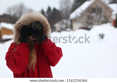 Photographer in winter, tourist girl in red jacket taking pictures of snowy town in Joensuu, Finland