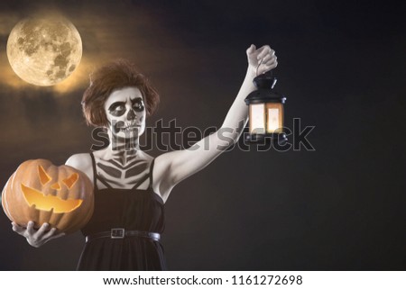 Girl with Halloween make up hold pumpkin and candlestick. Autumn