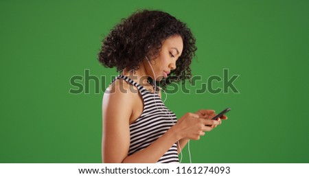 Casual millennial female listening to music on smartphone on green screen